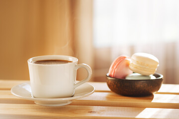 Cozy breakfast with cup of coffee and macaroons on rustic wooden table. 