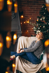 Woman sitting in chair by Christmas tree