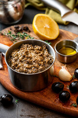 Tapenade in a bowl close-up and ingredients for making tapenade. French cuisine. Tapenade is made from olives, capers, anchovies and herbs.