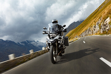 Motorbiker riding in Austrian Alps, dramatic sky. Travel and freedom, outdoor activities