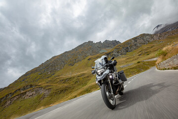 Motorbiker riding in Austrian Alps, dramatic sky. Travel and freedom, outdoor activities