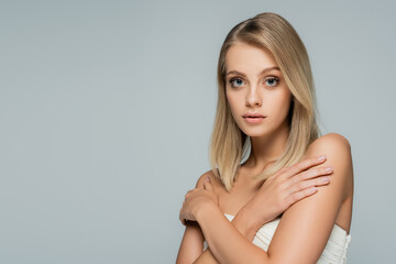 Naklejka premium young blonde woman with bare shoulders and natural makeup posing with crossed arms isolated on grey.