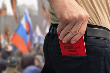 Man puts a military ID in the back pocket of his trousers. Mobilization in the Russian Federation. Contract service. The inscription on the document - "Military ID, Ministry of Defense."