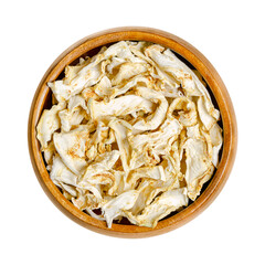 Celery root, dehydrated slices, in a wooden bowl. Celeriac, knob or turnip rooted celery, Apium graveolens var. rapaceum, a root vegetable, except with a bulbous hypocotyl with small roots attached.