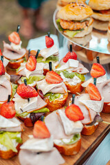 Sandwiches with camembert ham and strawberries on a wooden board