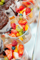 Fruit salad with berries in a glass bowl with a spoon
