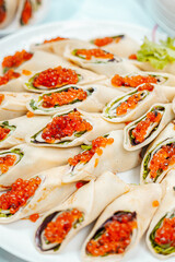 Pancakes with red caviar and herbs on a white dish