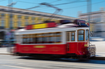 Red tram rides along the street of city. Passenger urban electric transport.