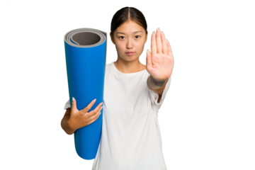 Young asian woman holding a mat isolated on green chroma background standing with outstretched hand showing stop sign, preventing you.
