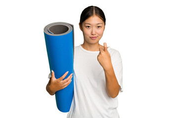 Young asian woman holding a mat isolated on green chroma background pointing with finger at you as if inviting come closer.
