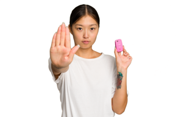 Young asian woman holding car keys isolated on green chroma background standing with outstretched hand showing stop sign, preventing you.