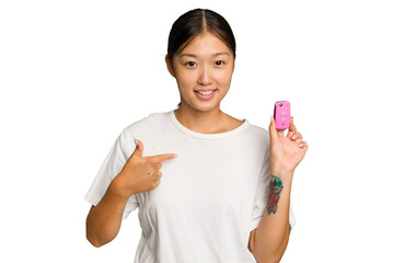 Young asian woman holding car keys isolated on green chroma background person pointing by hand to a shirt copy space, proud and confident