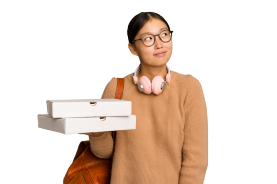 Young student Asian woman holding pizzas isolated on green chrome background dreaming of achieving goals and purposes