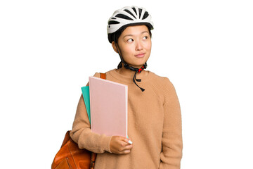 Young student asian woman wearing a bike helmet isolated on green chroma background dreaming of achieving goals and purposes