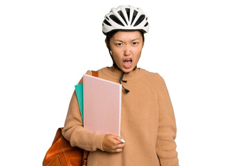 Young student asian woman wearing a bike helmet isolated on green chroma background screaming very angry and aggressive.