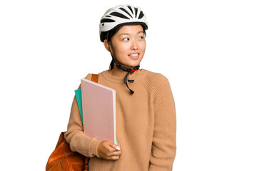 Young student asian woman wearing a bike helmet isolated on green chroma background looks aside smiling, cheerful and pleasant.
