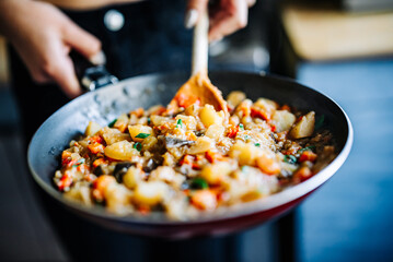 Woman cooking tasty vegetable stew in pan on kitchen