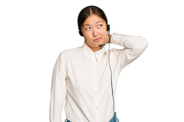 Telemarketer asian woman working with a headset isolated on green chroma background touching back of head, thinking and making a choice.