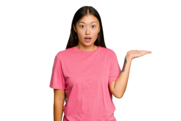 Young Asian woman isolated on green chroma background impressed holding copy space on palm.