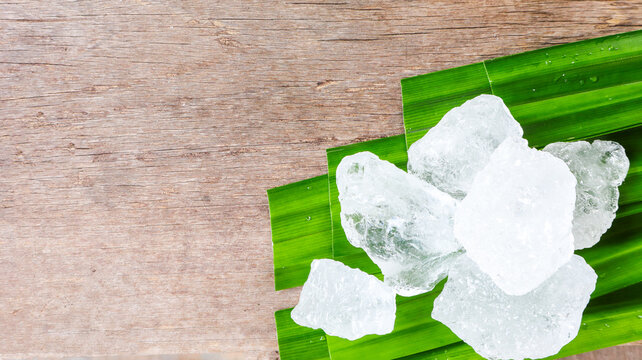 Crystal clear alum cubes or Potassium alum on green leaf. Chemical compound substance. Concept for beauty, spa and underarm treatment industrial.                                                      