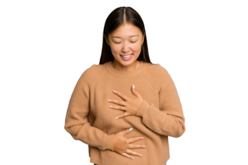 Young Asian woman isolated on green chroma background laughs happily and has fun keeping hands on stomach.