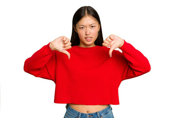 Young Asian woman isolated on green chroma background showing thumb down and expressing dislike.