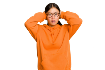 Young Asian woman isolated on green chroma background covering ears with hands trying not to hear too loud sound.