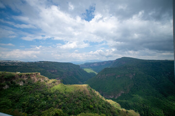 Naklejka premium ravine trees and vegetation, view of several mountains at different depths, blue sky and few clouds, mexico