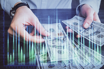 Multi exposure of financial graph drawing hologram and USA dollars bills and man hands. Analysis concept.