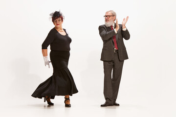 Tango. Handsome senior man and adorable middle age woman in vintage style autumn outfits dancing...