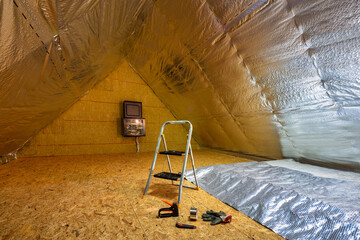 Laying the thermal insulation foil on the insulated attic in the house
