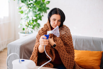 a young woman holding a steam nebulizer inhaler in her hand, treats flu and asthma from the...