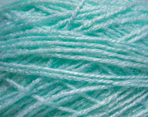 Macro texture of woolen turquoise thread, close-up, copy space. Macro Photography of a coil with threads. Sewing background, screensaver. Abstraction, interweaving of natural threads