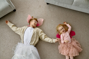 Funny dressed father and daughter lying on floor