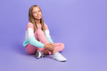 Full length photo of funny adorable small girl wear sweatshirt sitting floor empty space isolated...