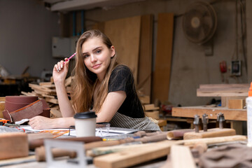 Portrait of a female carpenter drawing on paper for designing and building furniture in a furniture...