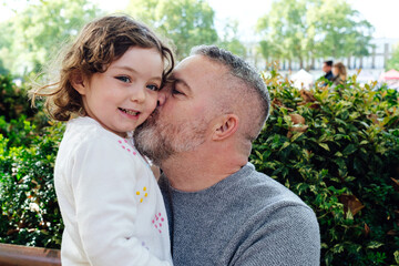 Fototapeta premium Father is kissing his daughter in the park.