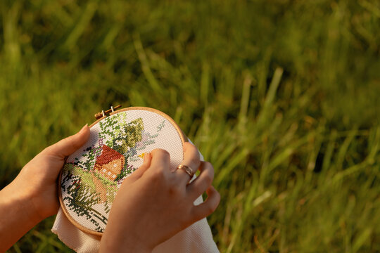 Cross-stitch in female hands in outdoors, close up