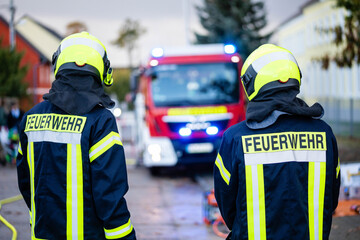 Feuerwehrleute vor Einsatzfahrzeug mit Blaulicht