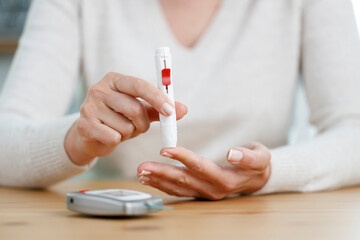 Young woman doing blood sugar test at home