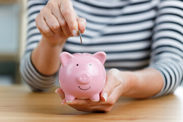 Woman putting money into piggy bank. Concept of money saving and budgeting..