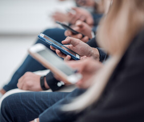 young employees with smartphones sitting in the same row