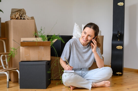 Cheerful woman speaking on smartphone during relocation