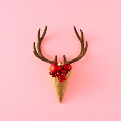 Creative layout made of reindeer antlers, Christmas decoration and ice cream cone on pastel pink...