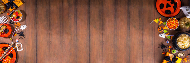 Halloween sweets and snacks table. Set of Halloween dinner party foods, candy, snacks, with holiday costume decorations, pumpkin buckets, wooden background top view copy space