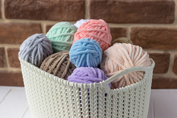 Basket with coils of plush yarn in pastel colors. Knitter's basket on a white table