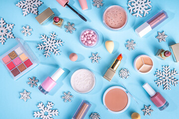 Winter make up set on light blue background, with artificial snowflakes and Christmas tree branches. Various makeup professional cosmetics - shadows, lipstick, mascara, blush. Christmas beauty sale