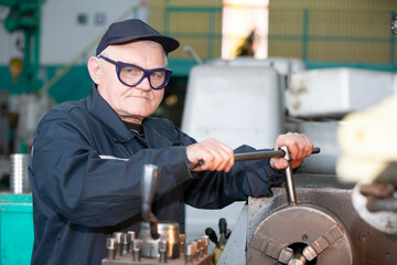 Turning production An elderly man works at a lathe. Turning works.