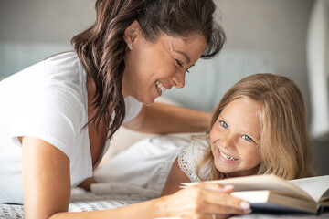 Mother and little girl playing in bedroom