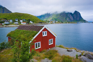 Traditionelles rotes Holzhaus mit Torfdach an der Küste von Reinefjorden, Lofoten, Norwegen